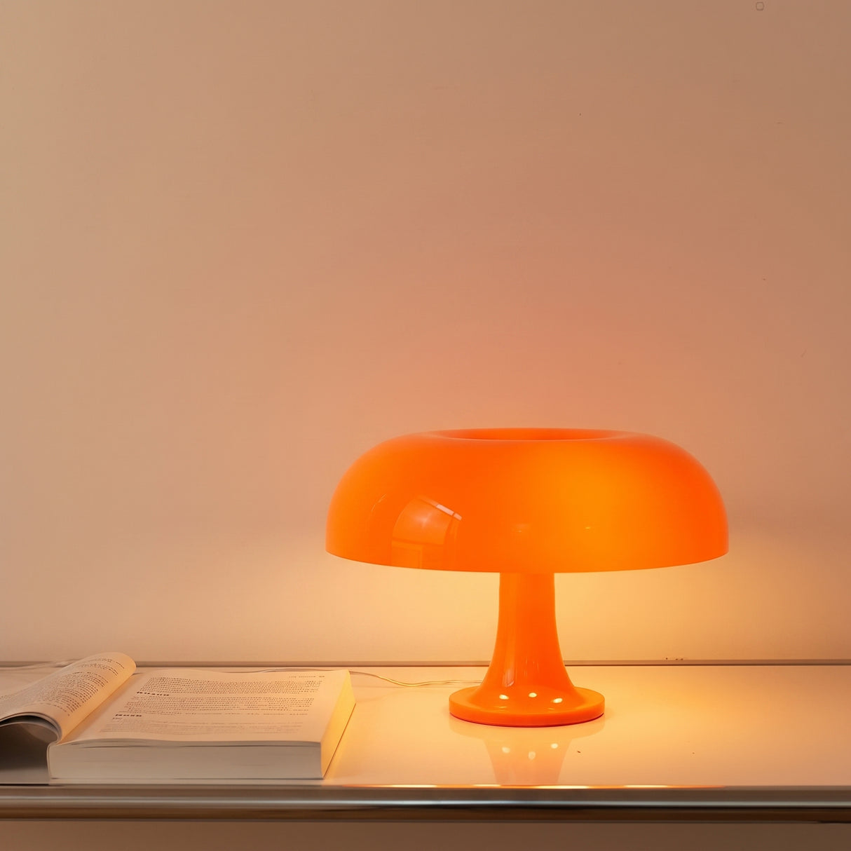 Orange mushroom table lamp glowing on a desk beside an open book
