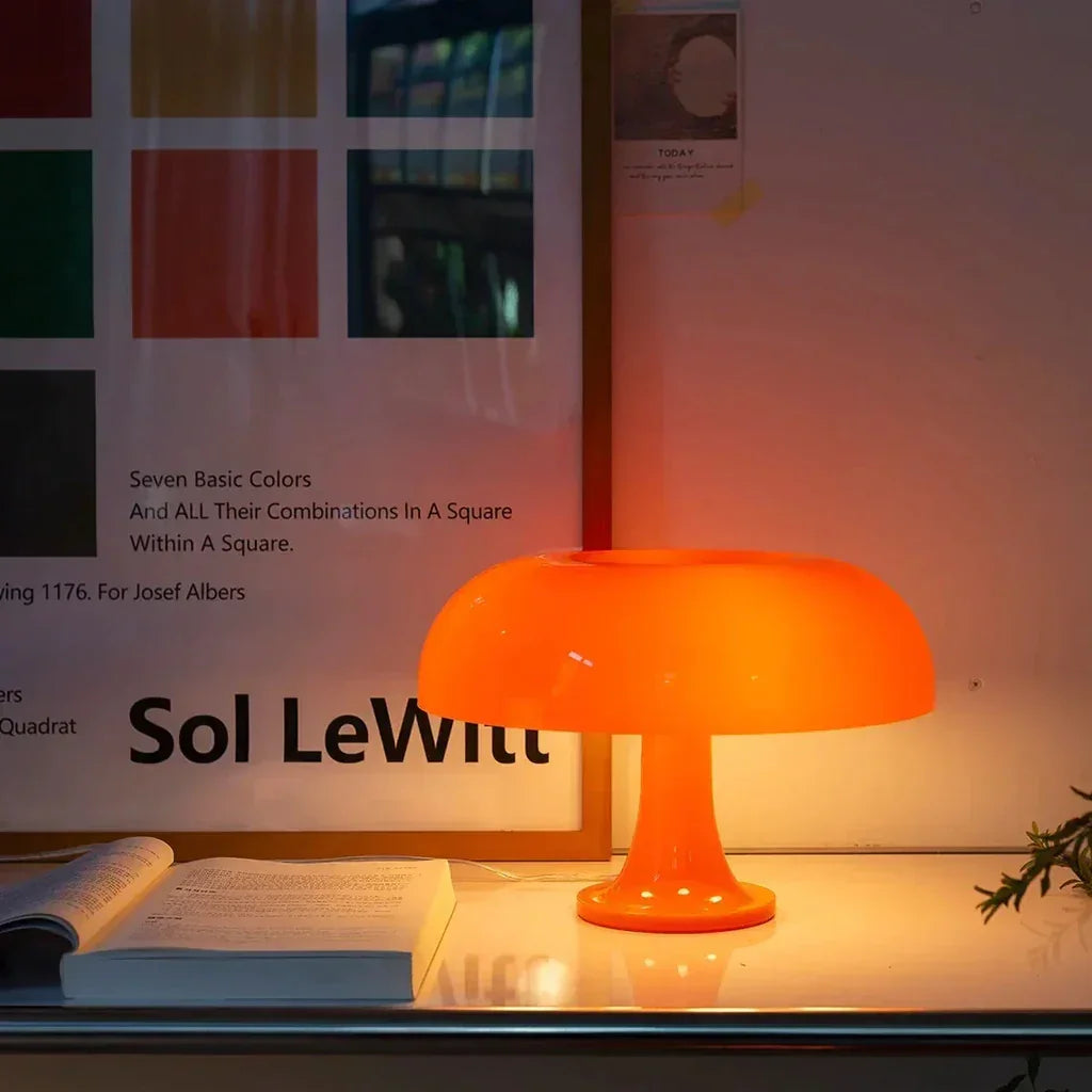 Orange mushroom table lamp on a timber desk below a bookshelf