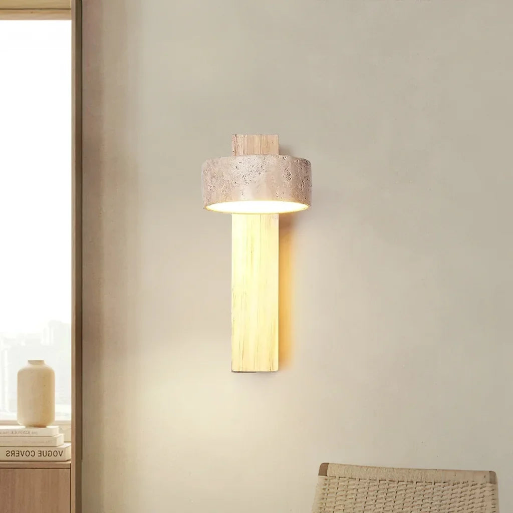 Natural wood wall sconce with upright travertine shade beside a woven chair