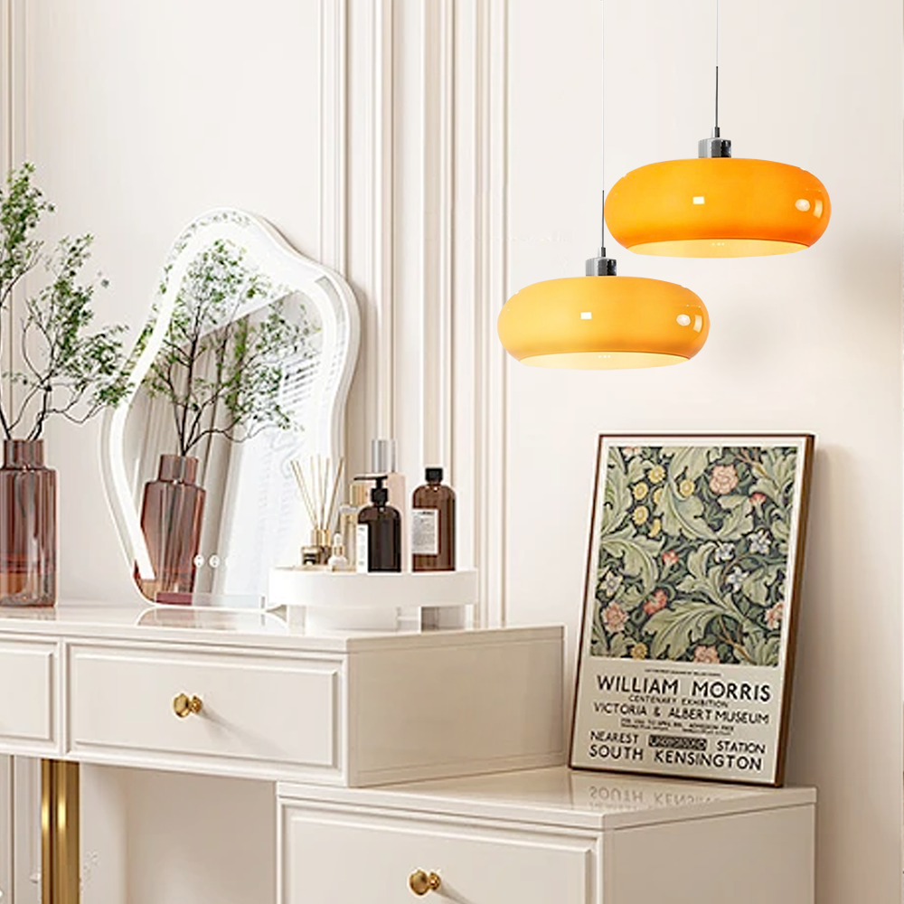 Orange glass pendant light above a wooden dining table with white tulips