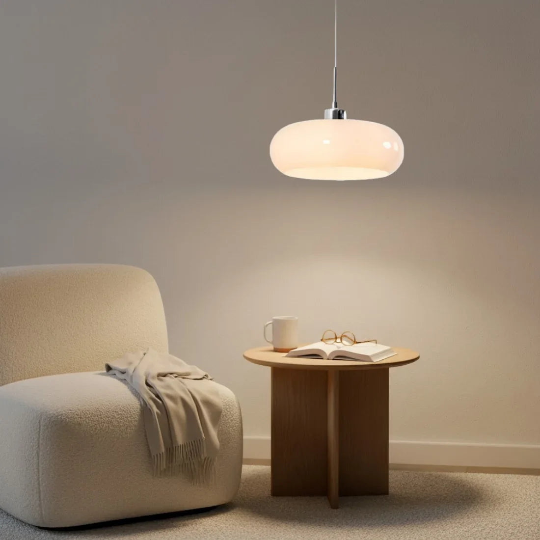 Orange glass pendant light above a small round table between two wooden chairs