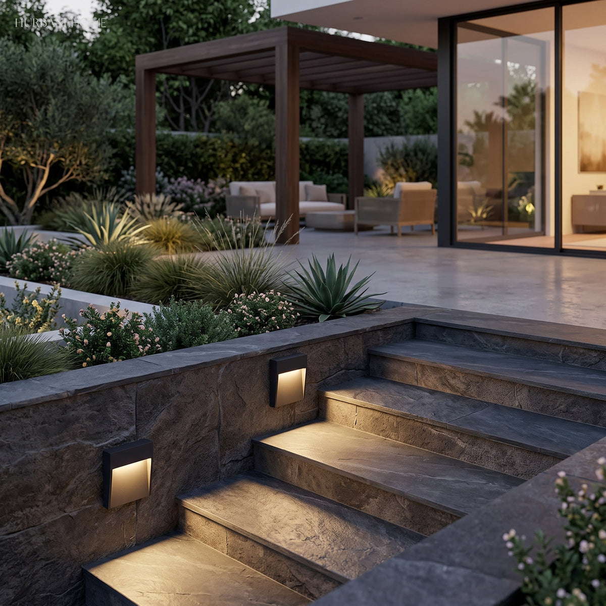 Step lights lining stone garden stairs beside a planted terrace