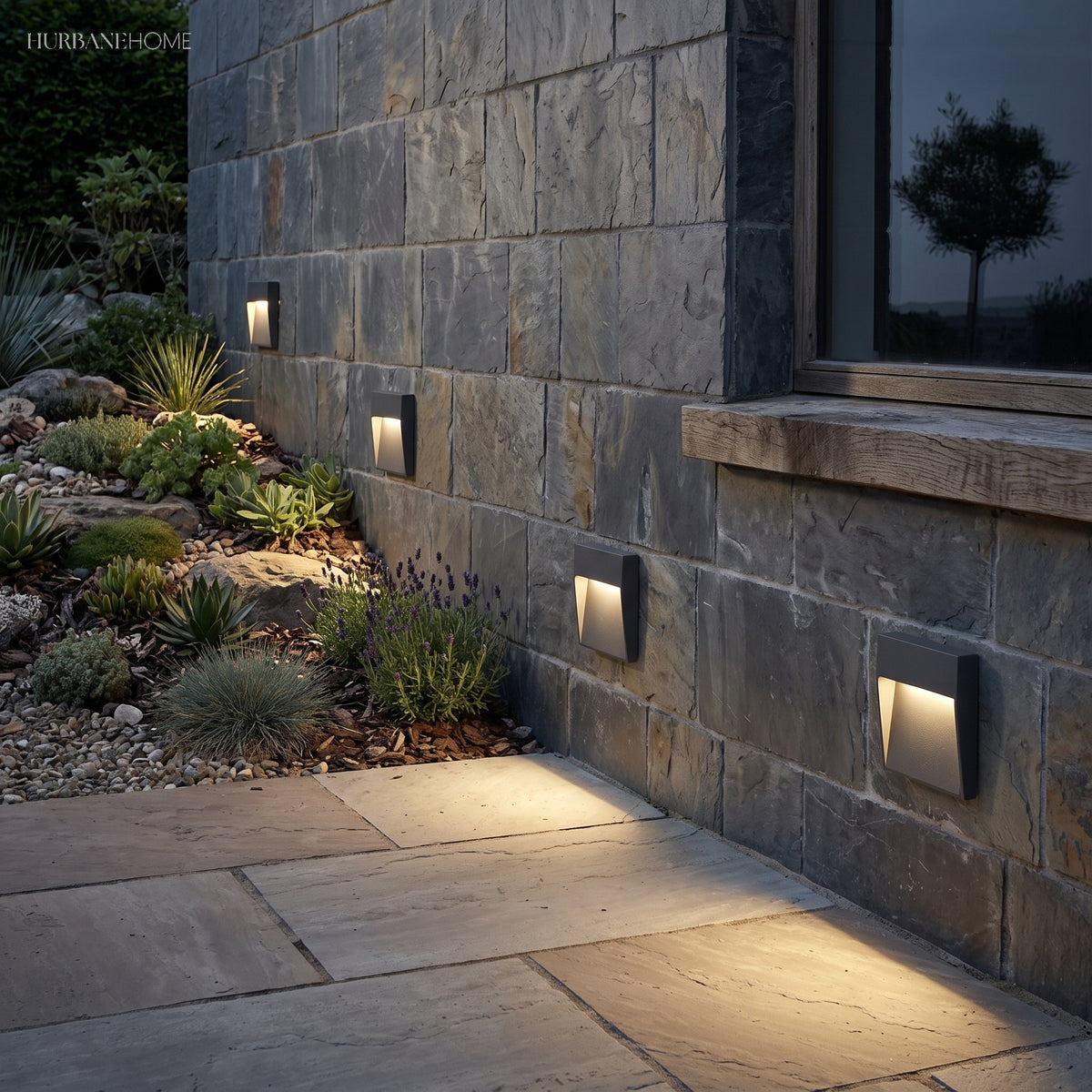 Step lights set into a stone wall above a paved path
