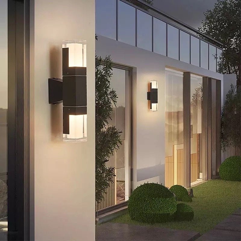 Outdoor wall sconce with a lit clear prism tube on a dark house wall