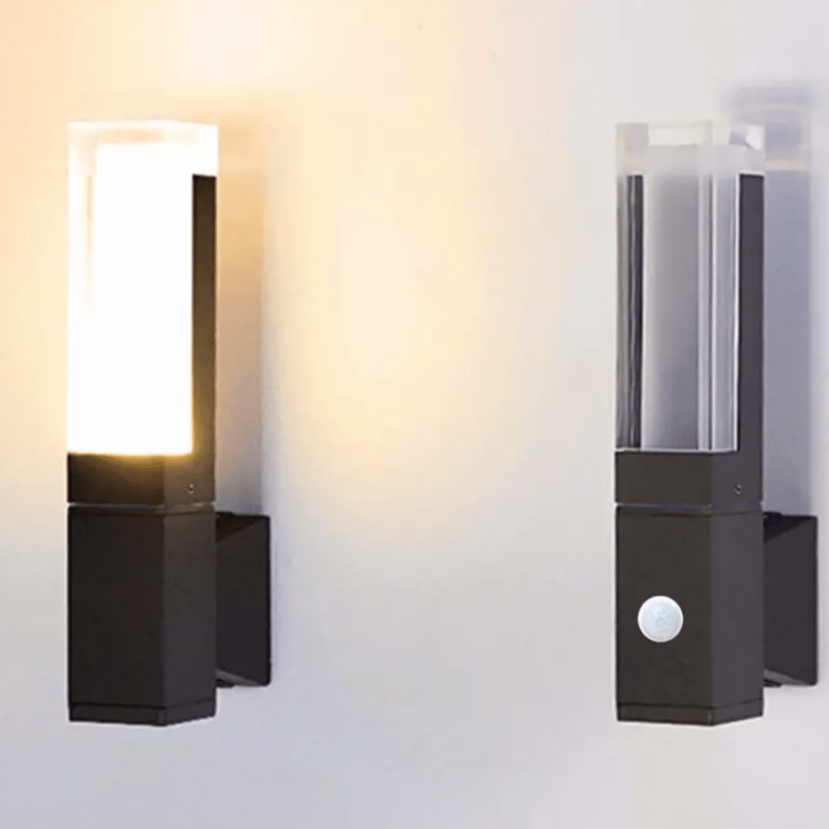 Two prism wall sconces lit on a wall with the sensor version in front
