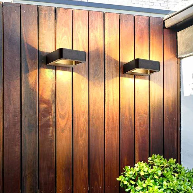 Two outdoor wall sconces lit on a vertical timber clad wall