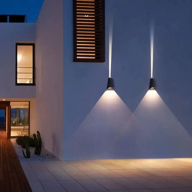 Two outdoor sconces casting cones of light on a pale house facade
