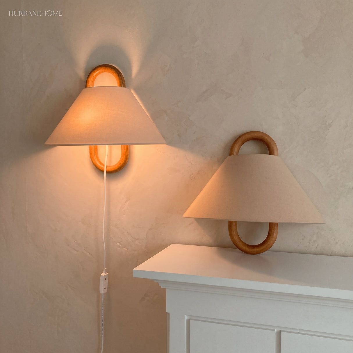 Pleated fabric wall sconce with beechwood mount glowing softly on a wall
