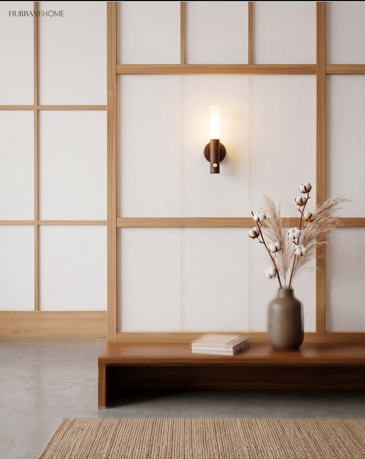 Lit tube sconce on a white wall beside a shoji screen and bench