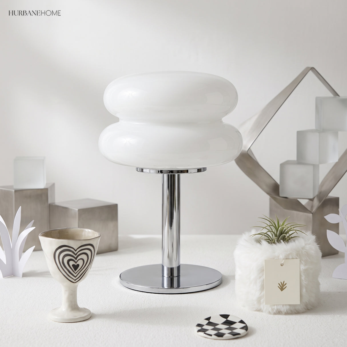 White glass table lamp on a styled desk with sculptural objects