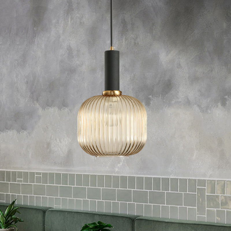 Amber ribbed pendant lit against a wall of green subway tiles