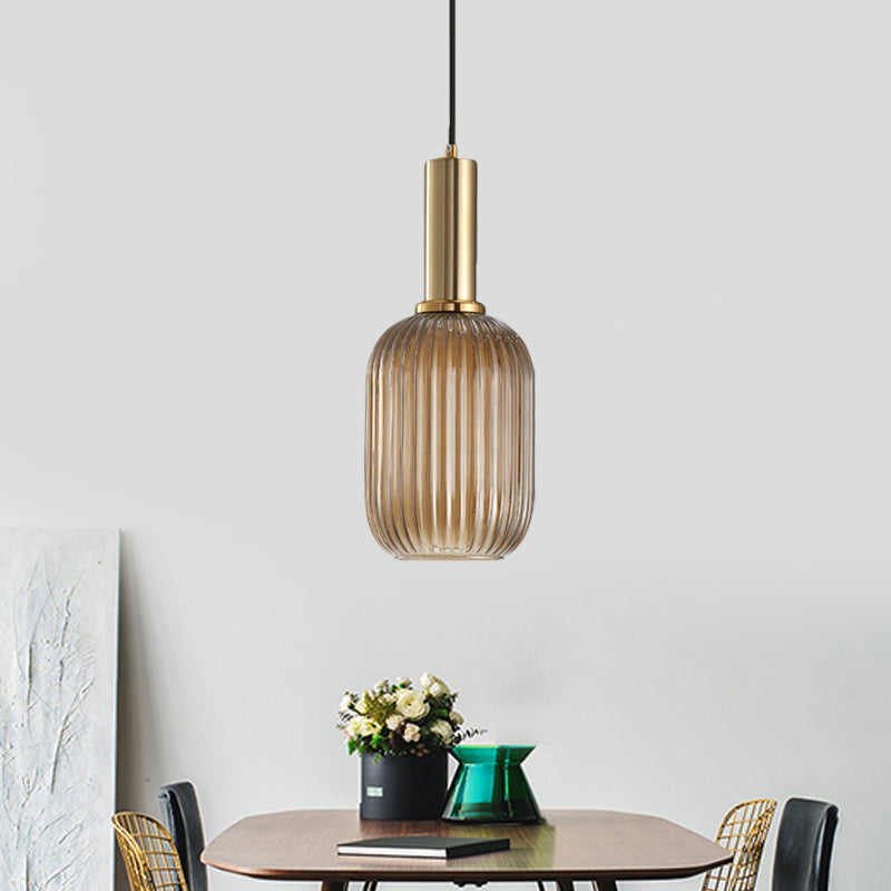 Amber ribbed pendant lit above a dining table and potted plant