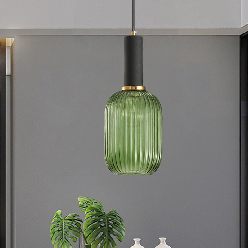 Green ribbed pendant lit on a grey wall beside a leafy plant