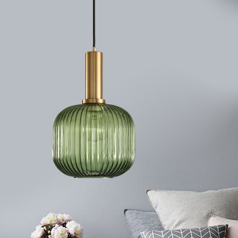 Green ribbed pendant lit beside a bed made up in pale linen
