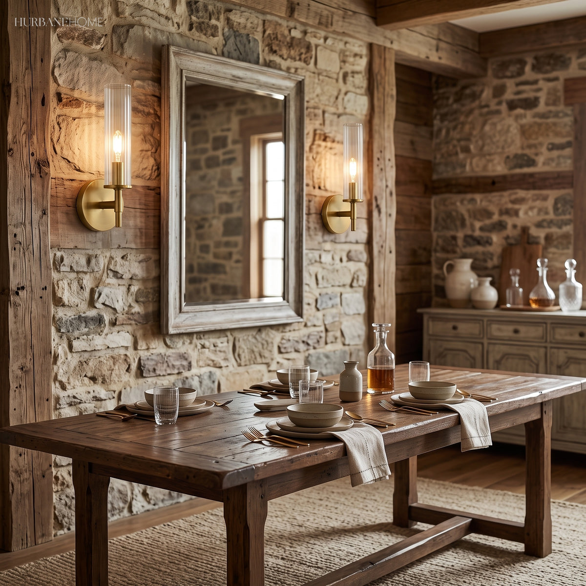 Two brass tube sconces on stone walling above a rustic dining table