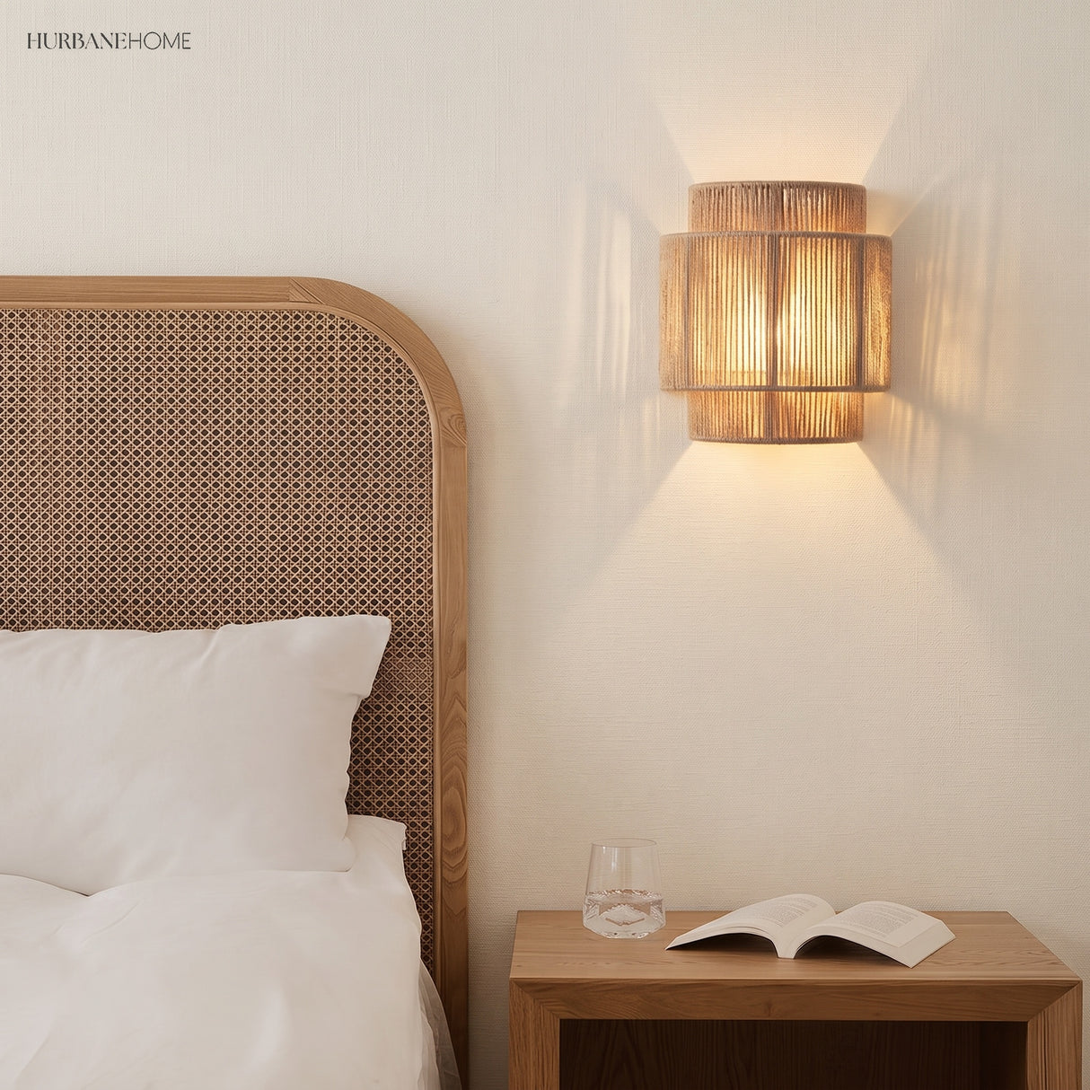 Rope wall lamp above a bedside table beside a rattan headboard