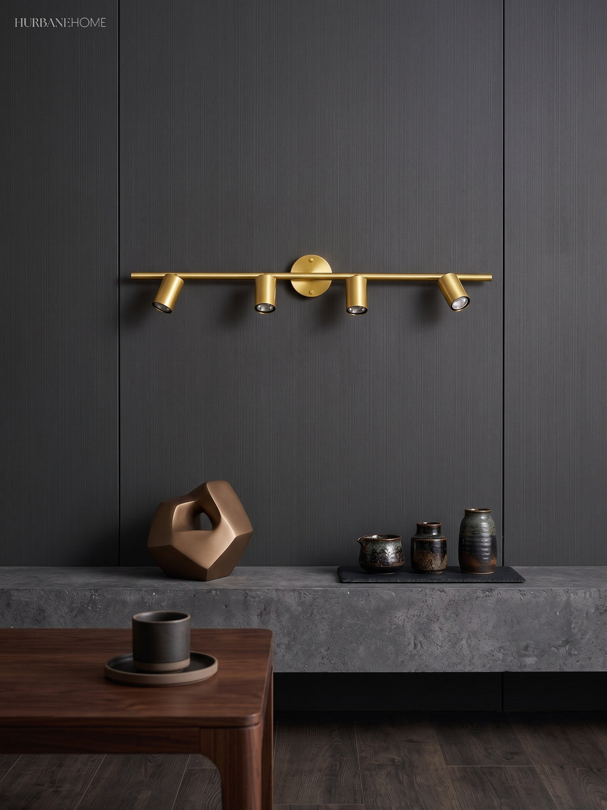 Brass spotlight bar with four heads lit on a dark panelled wall above a table
