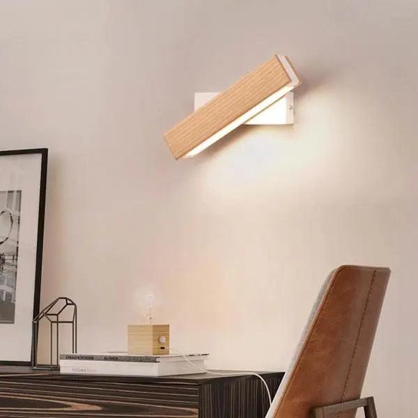 Oak bar sconce tilted down over a framed picture and desk