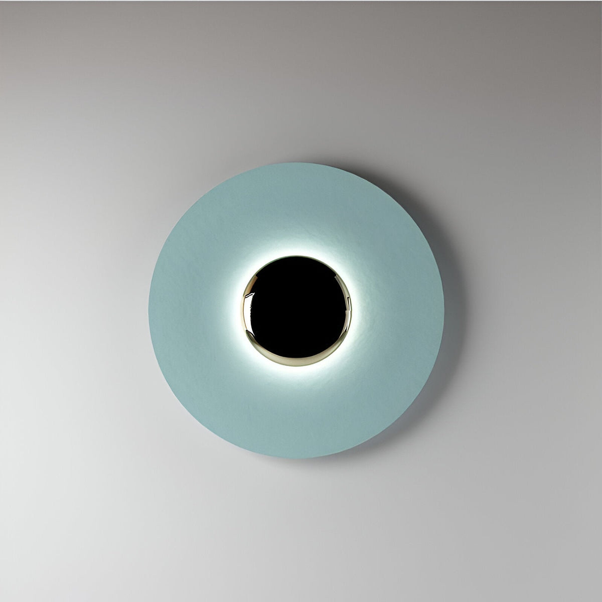 Blue disc sconce with a black centre lit on a pale wall