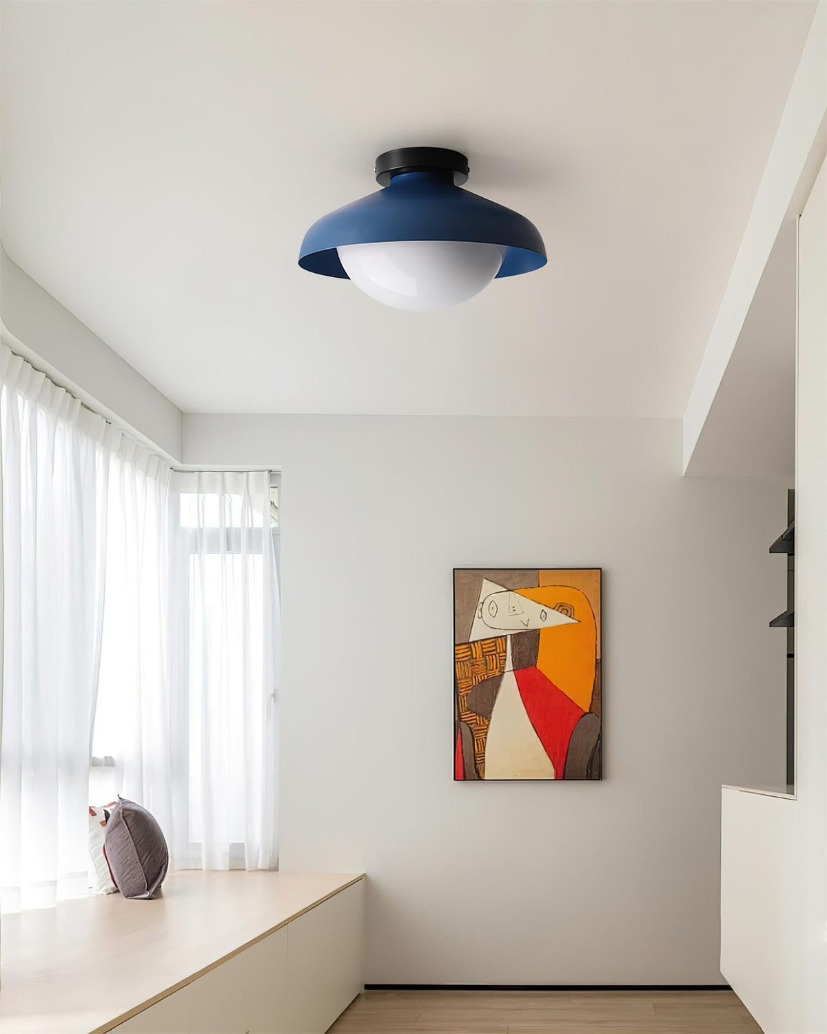 Blue dome ceiling light in a bright room above a window bench and framed print