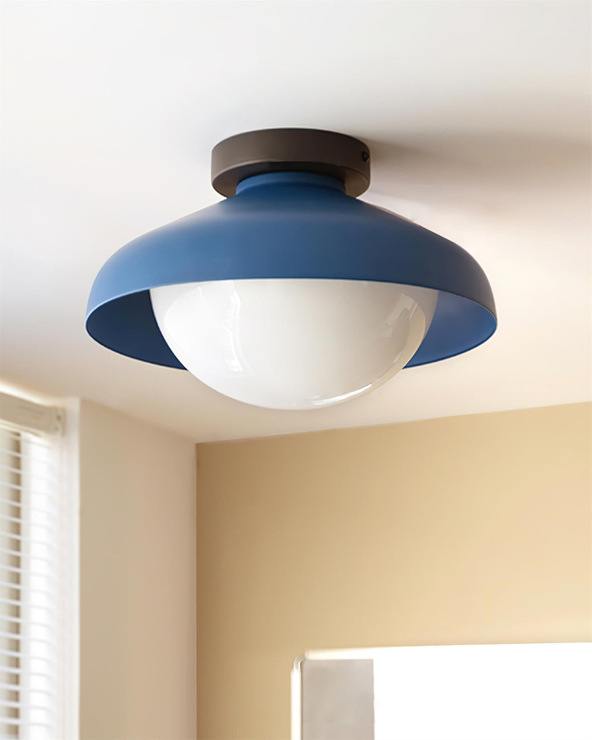 Blue dome ceiling light mounted on a white ceiling beside a window blind