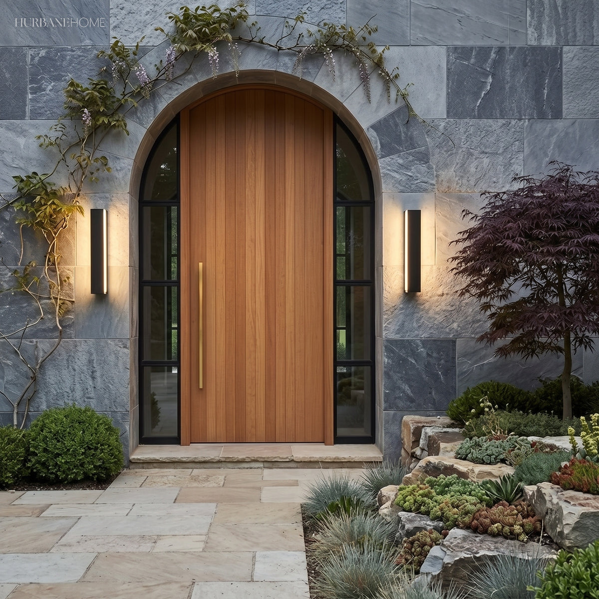 Pair of linear lights flanking an arched timber front door in stone cladding