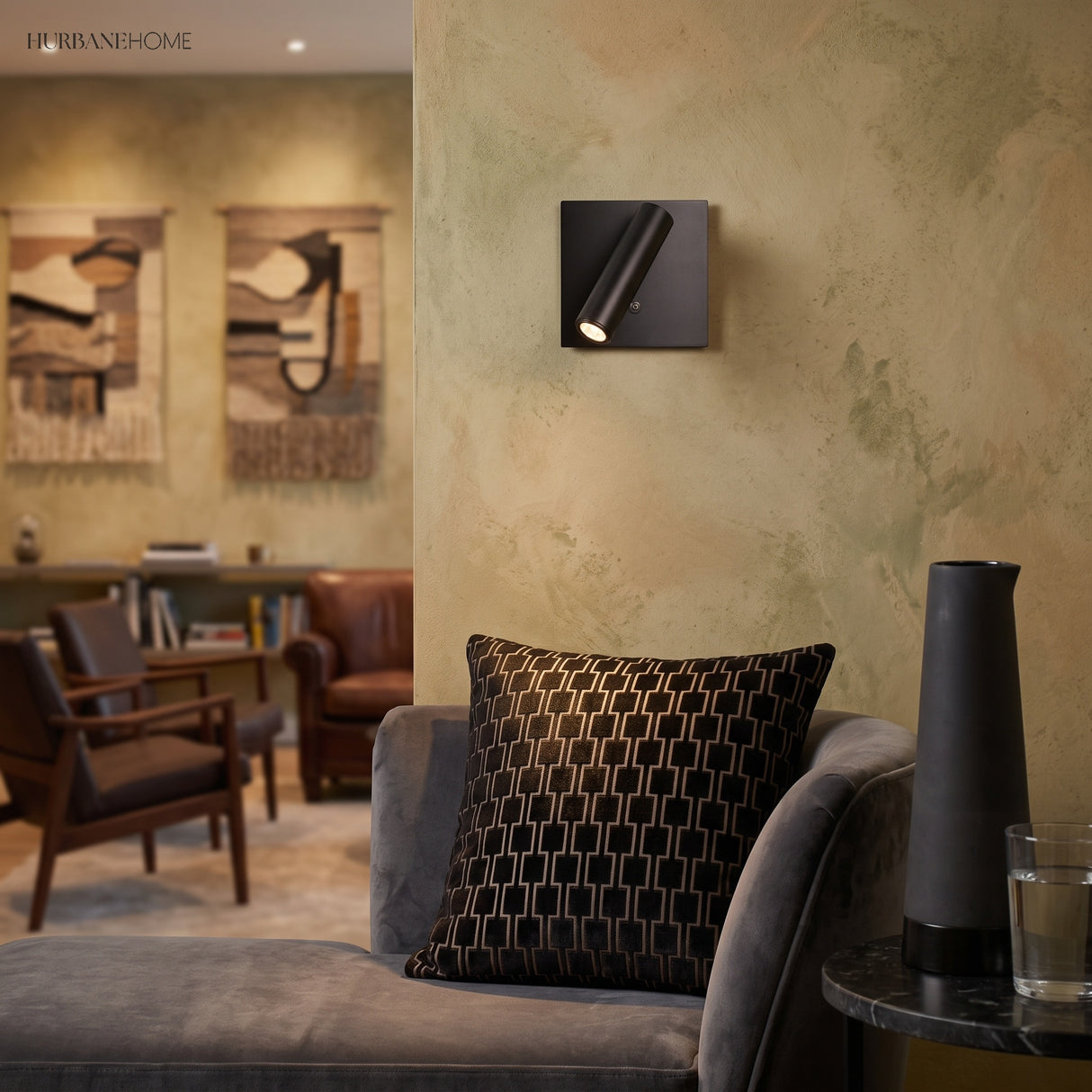 Black square switched sconce on textured wall above a grey sofa