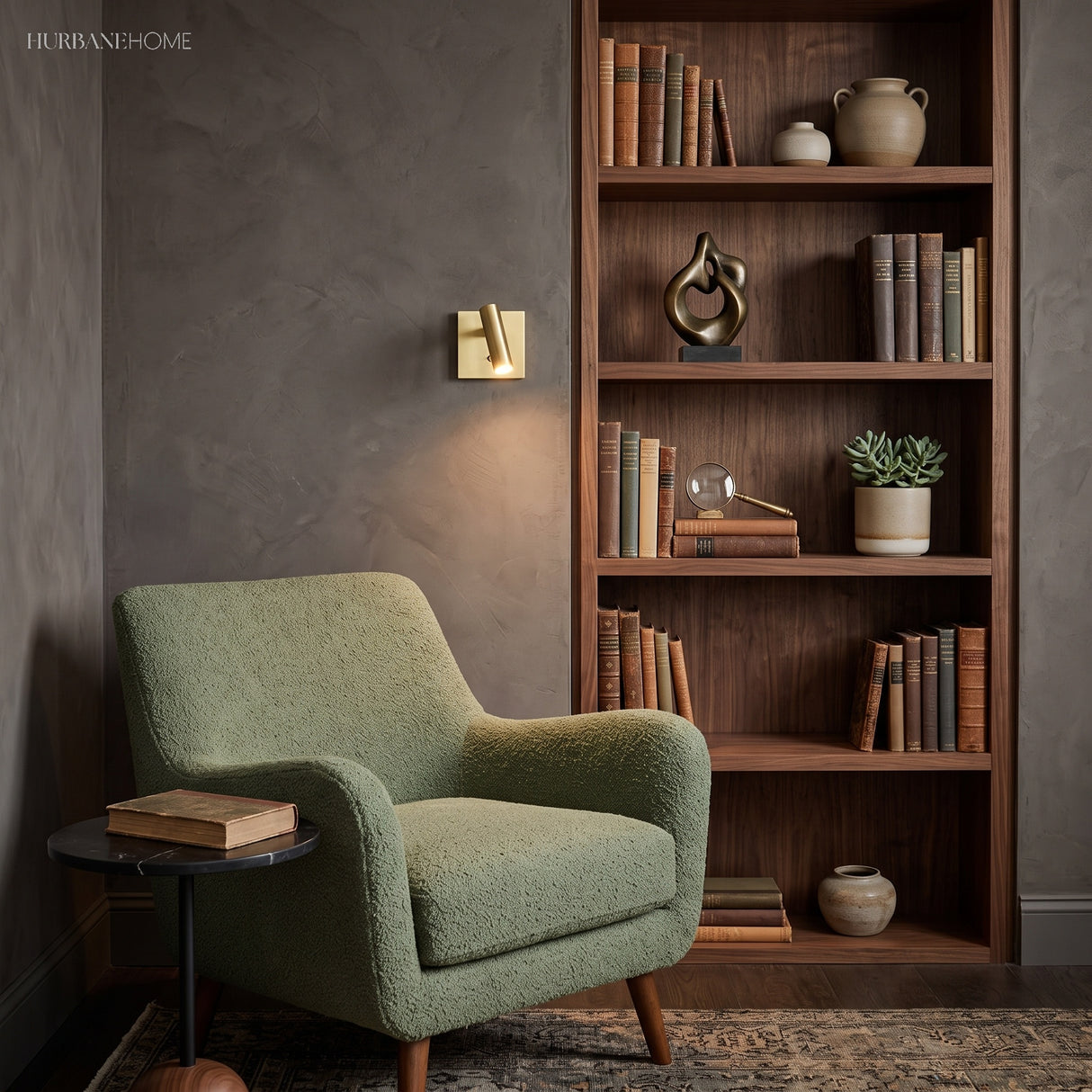 Brass square switched sconce beside a bookcase and green armchair
