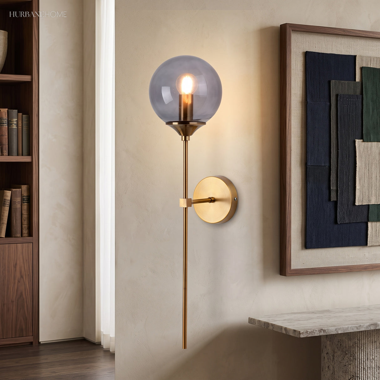 Smoke grey glass globe wall sconce lit beside framed wall art