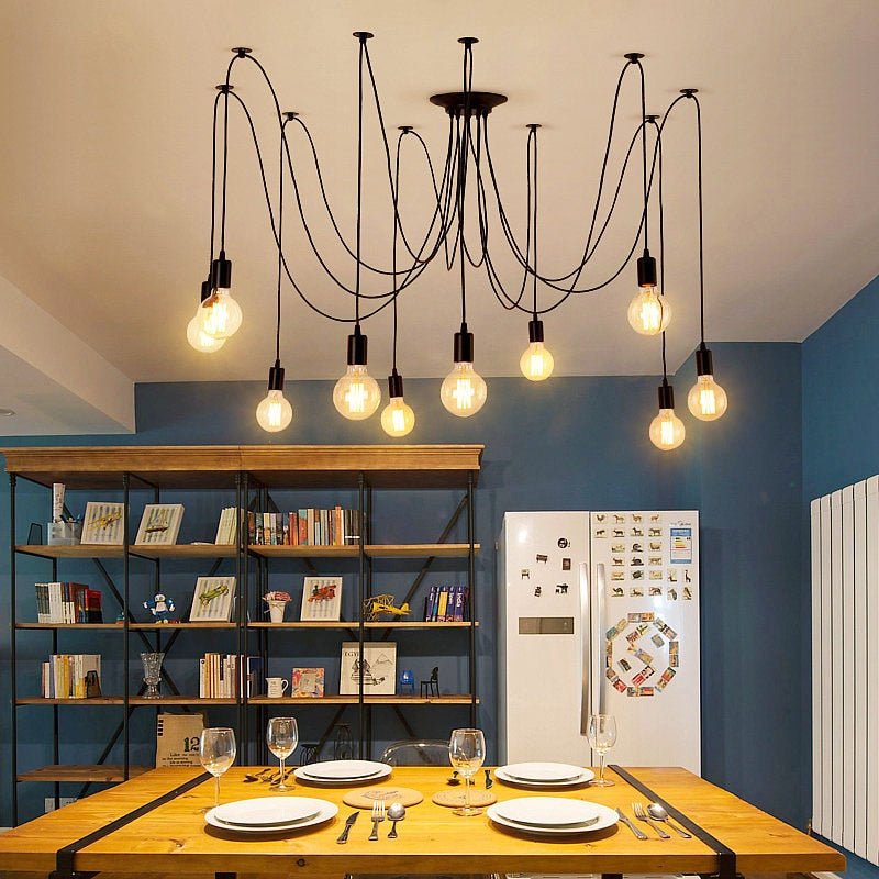 Spider chandelier with long cables lit above a dining table in a blue room