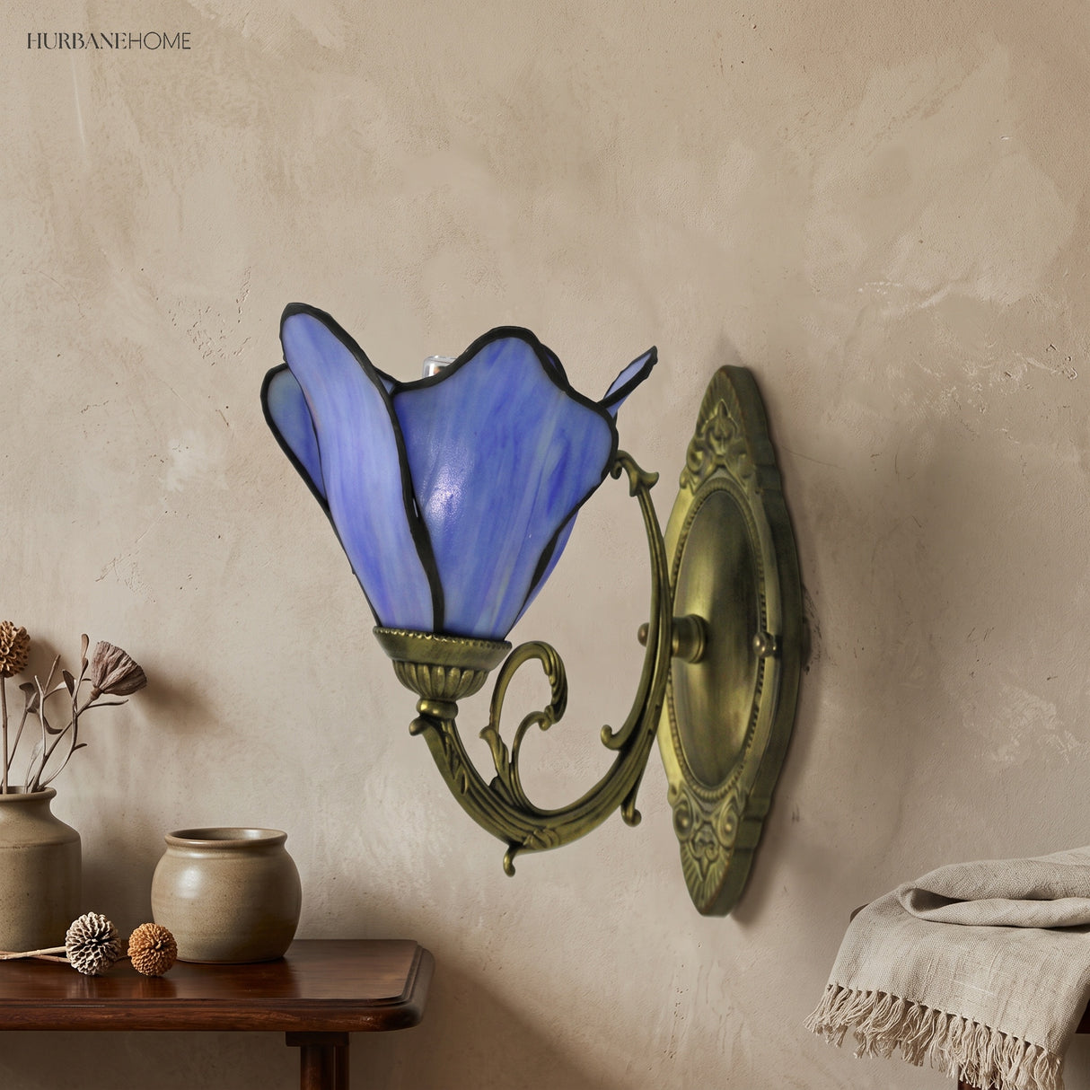 Blue art glass petal wall sconce above a timber console in a calm nook