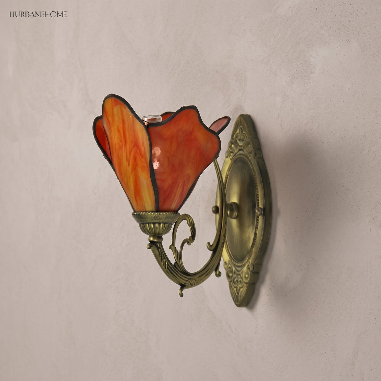 Close view of a red variegated glass petal shade and scrolled bronze arm