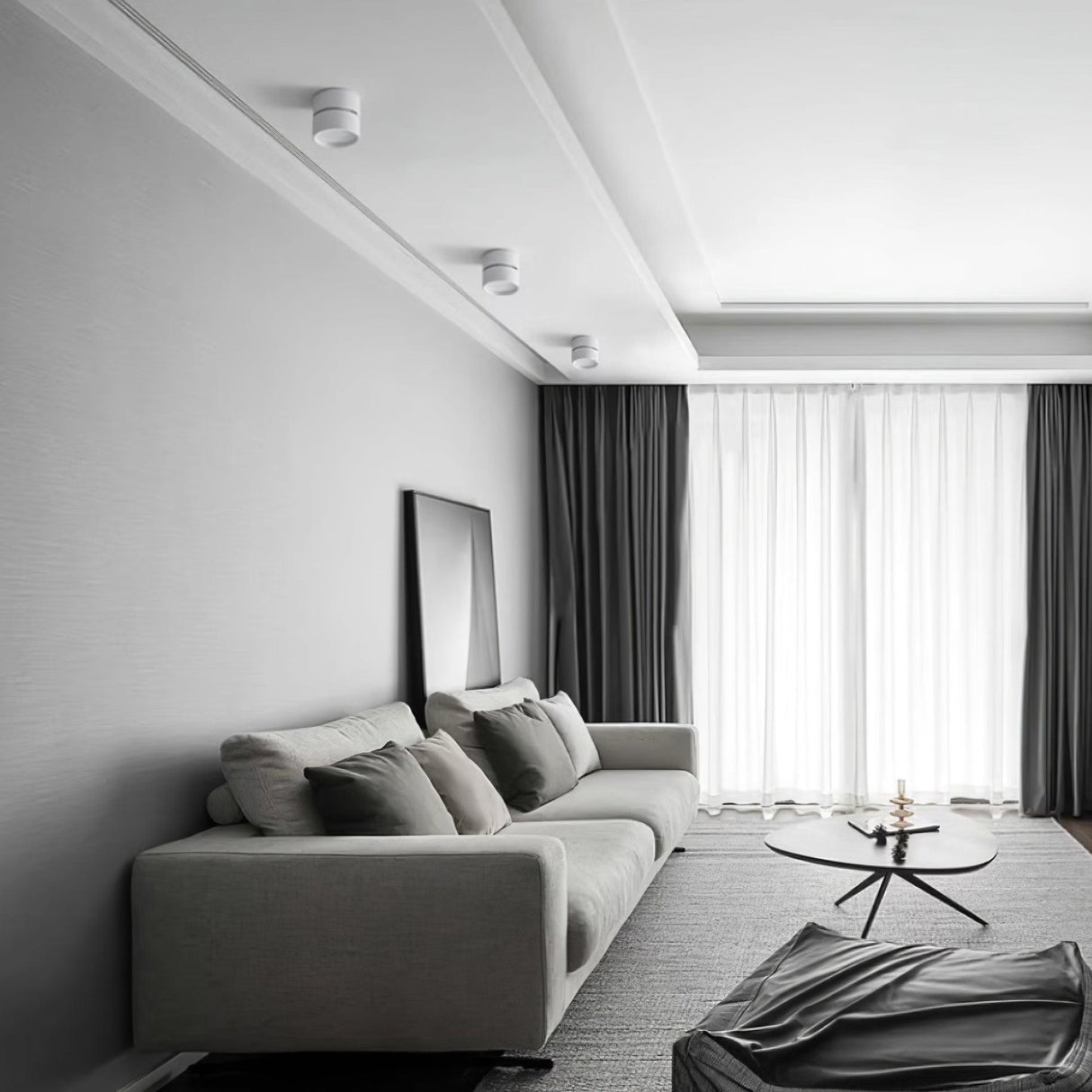 Surface mounted spot lights on a grey bedroom ceiling above a sofa and framed art