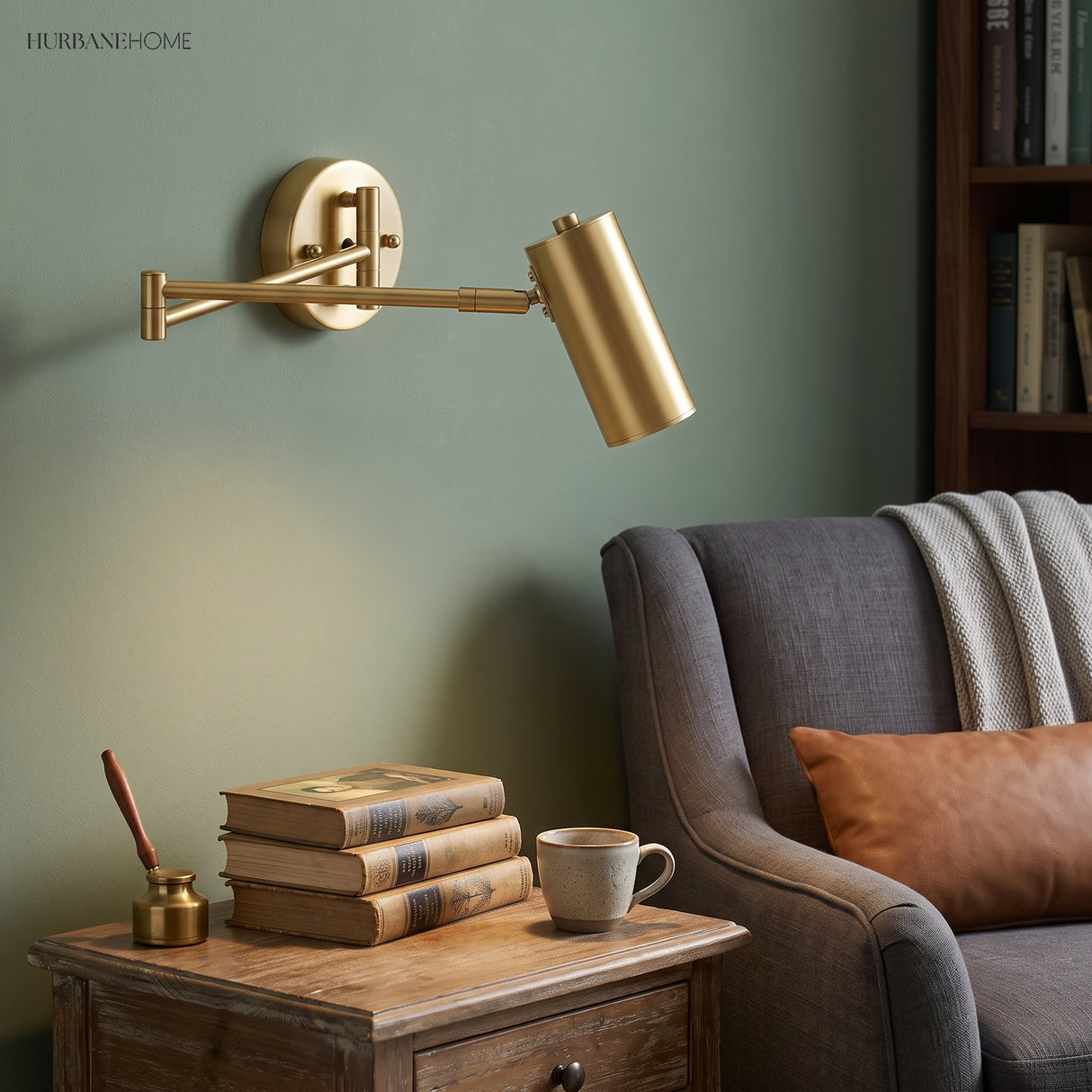 Gold swing arm sconce lit beside an armchair in a green room