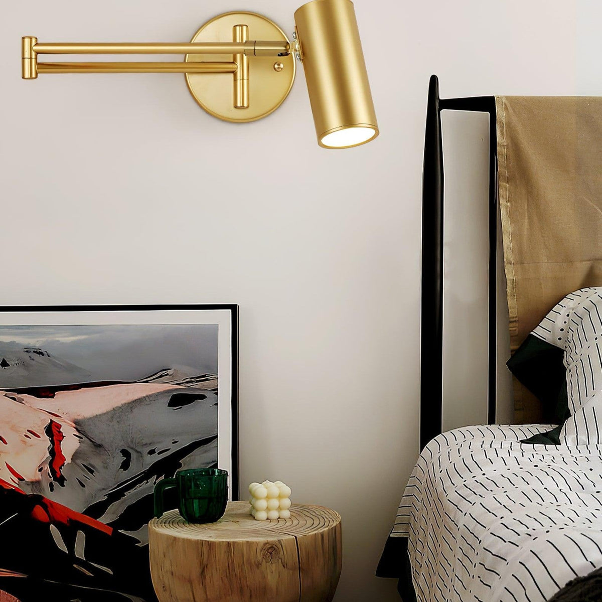 Two gold swing arm sconces above a bed with a framed print