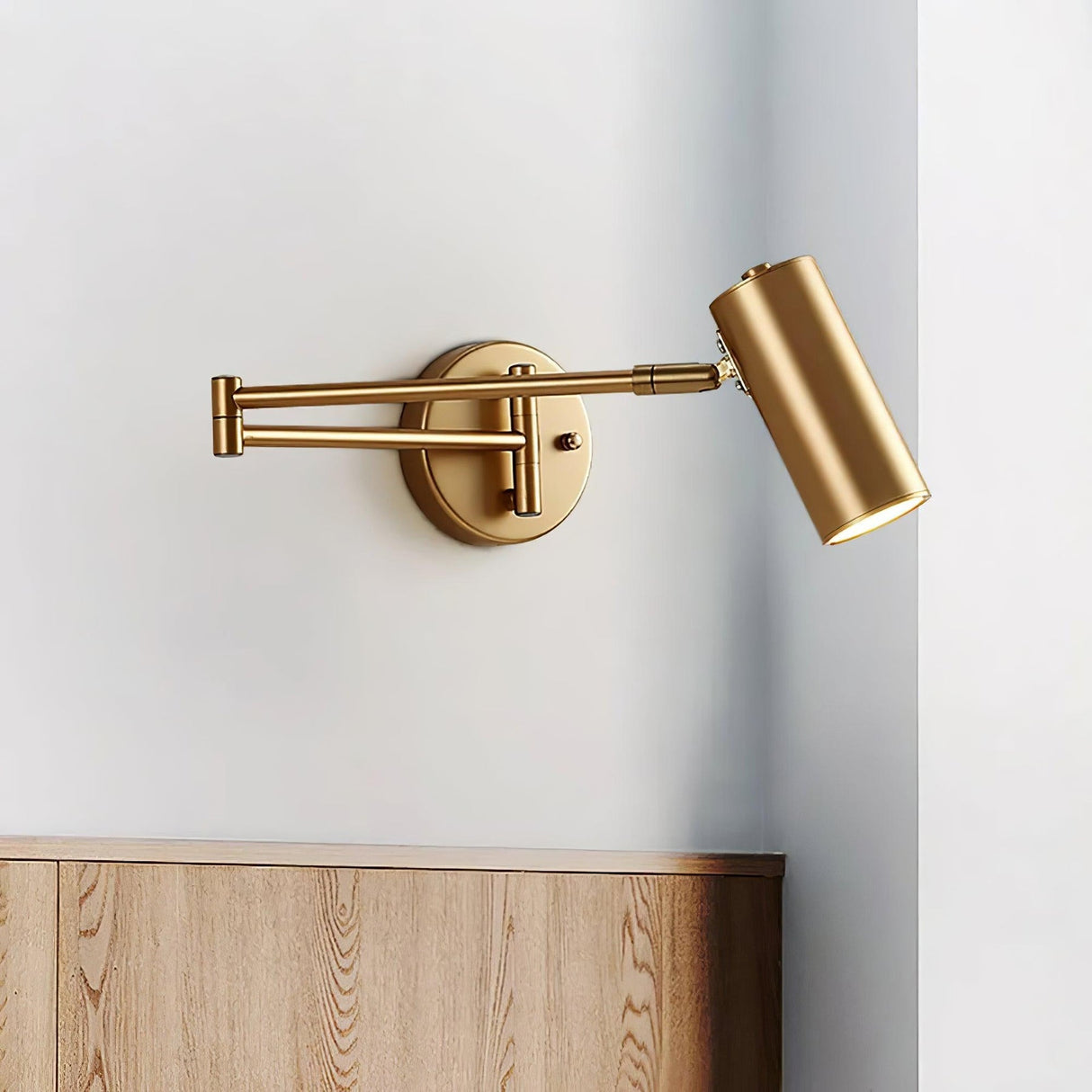 Gold swing arm sconce extended over a low wooden cabinet