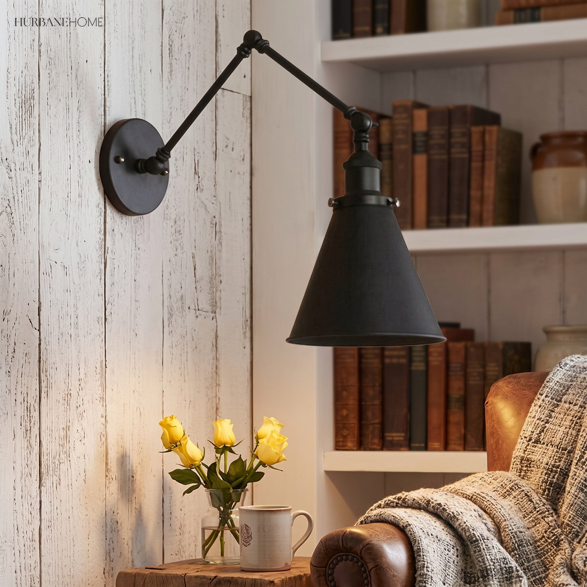 Black swing arm sconce lit warm beside books and a leather chair