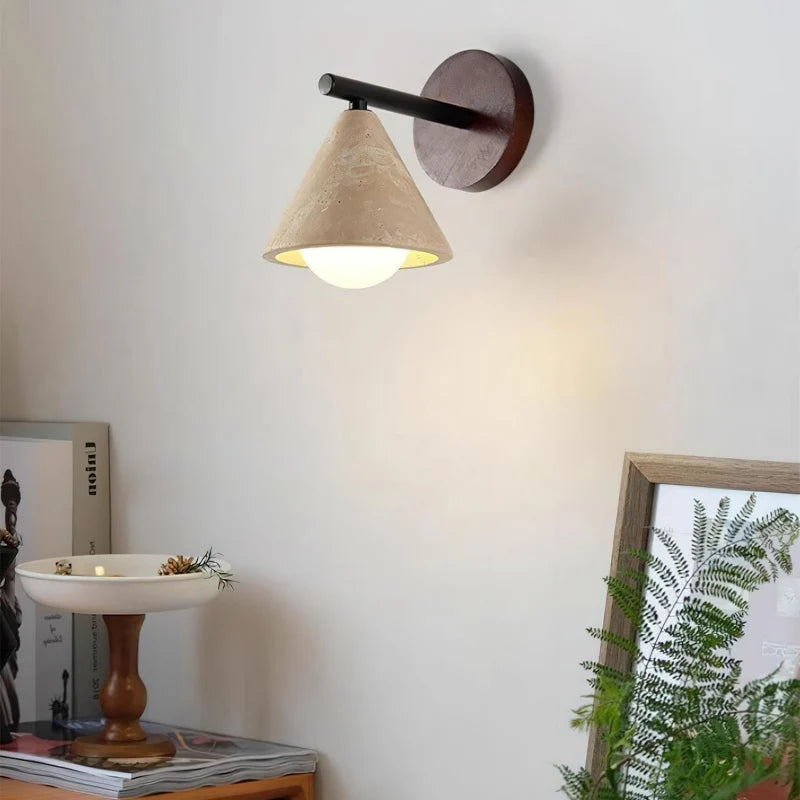 Travertine cone shade wall sconce lit warm on a neutral wall