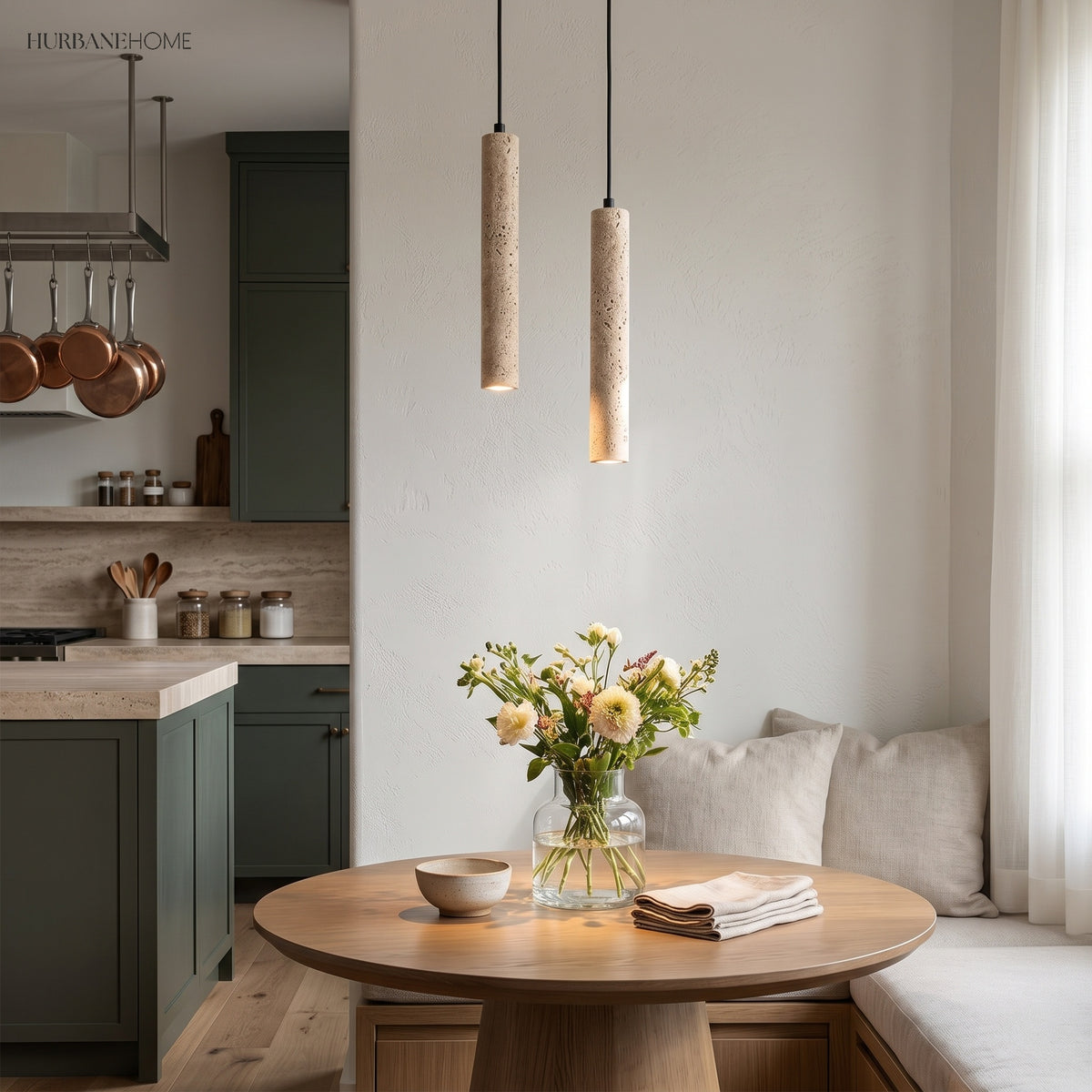 Two travertine cylinder pendants above a round table in a green kitchen
