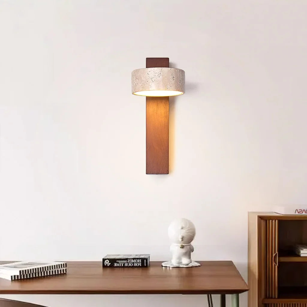 Walnut wall sconce with travertine shade above a desk and small white figurine