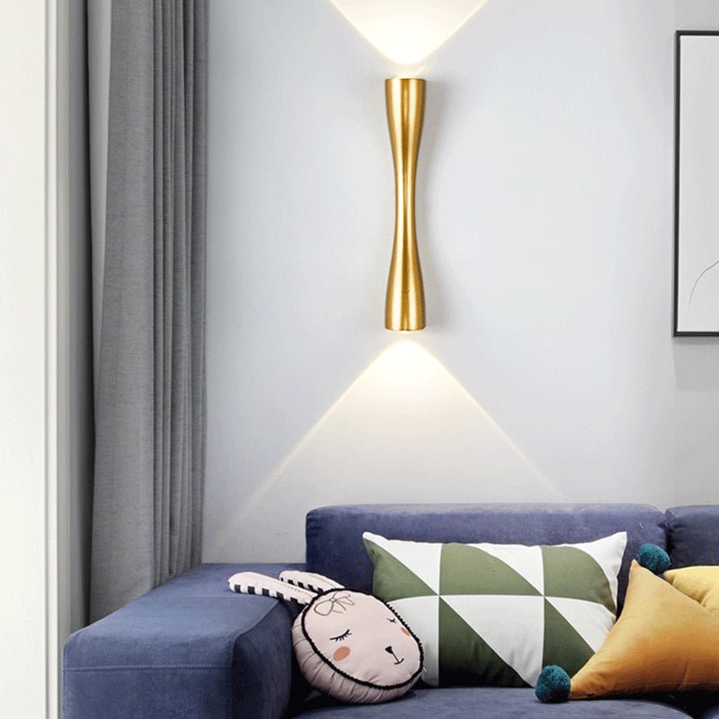Gold slim wall light lit above a sofa in a grey living room