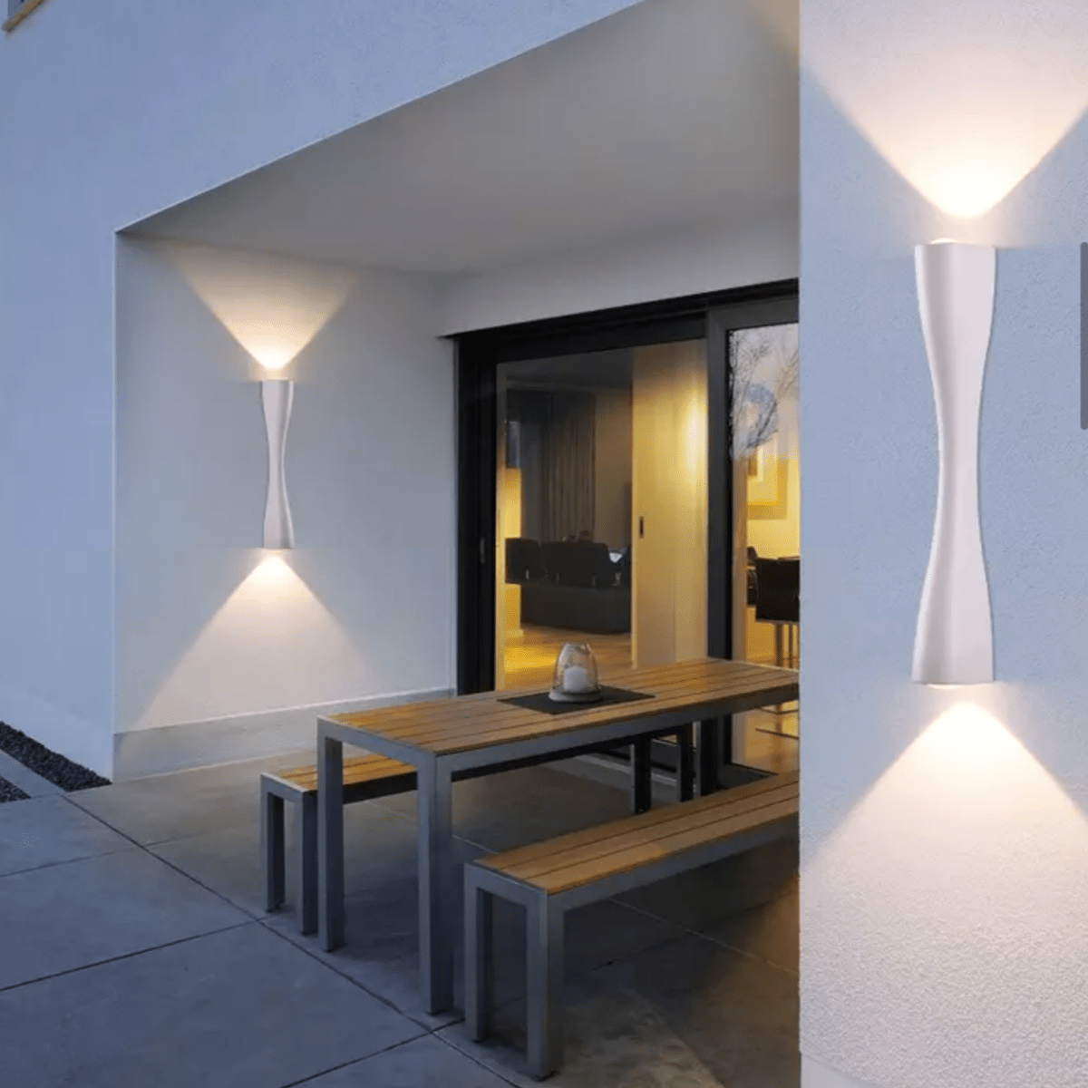 Gold slim wall light on an outdoor wall beside a covered dining terrace