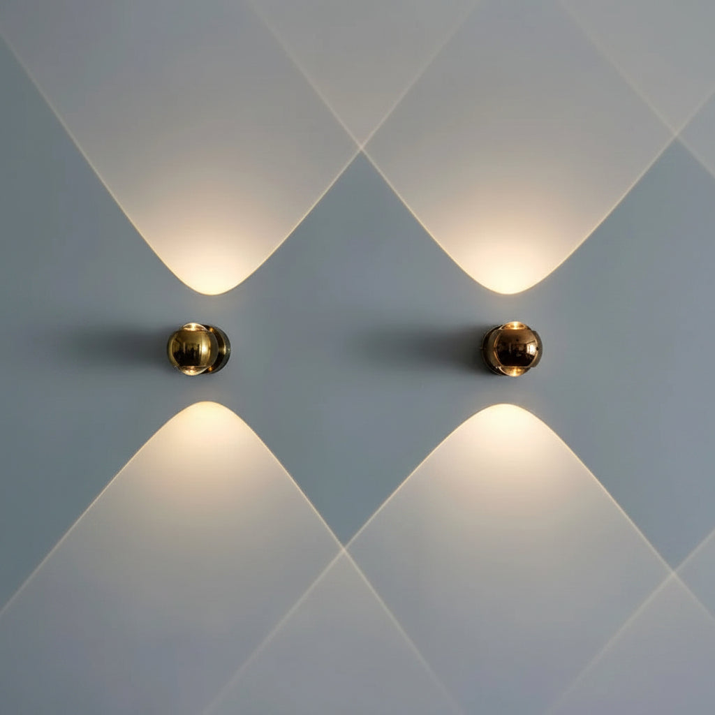 Two gold orb sconces lit side by side on a soft blue wall