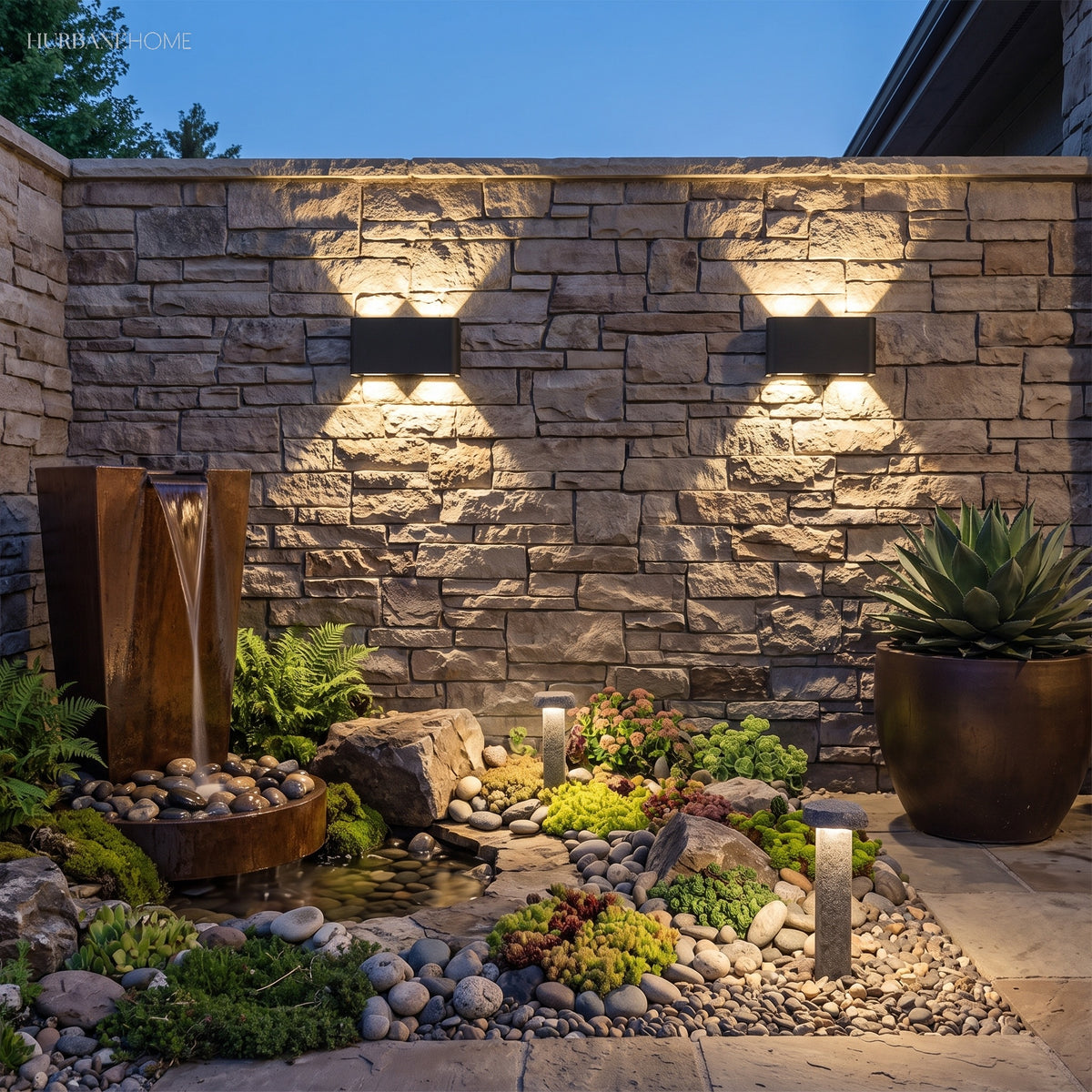 Pair of up and down lights on a stone wall above a planted rock garden
