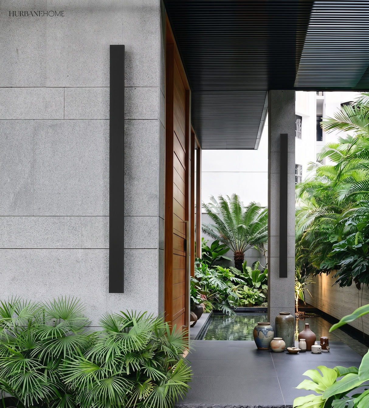 Linear LED wall light on a stone entry wall with tropical planting