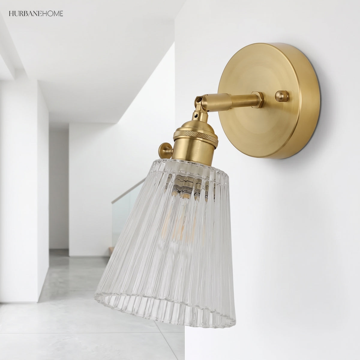 Angled brass wall sconce with ribbed glass shade on a white hallway wall