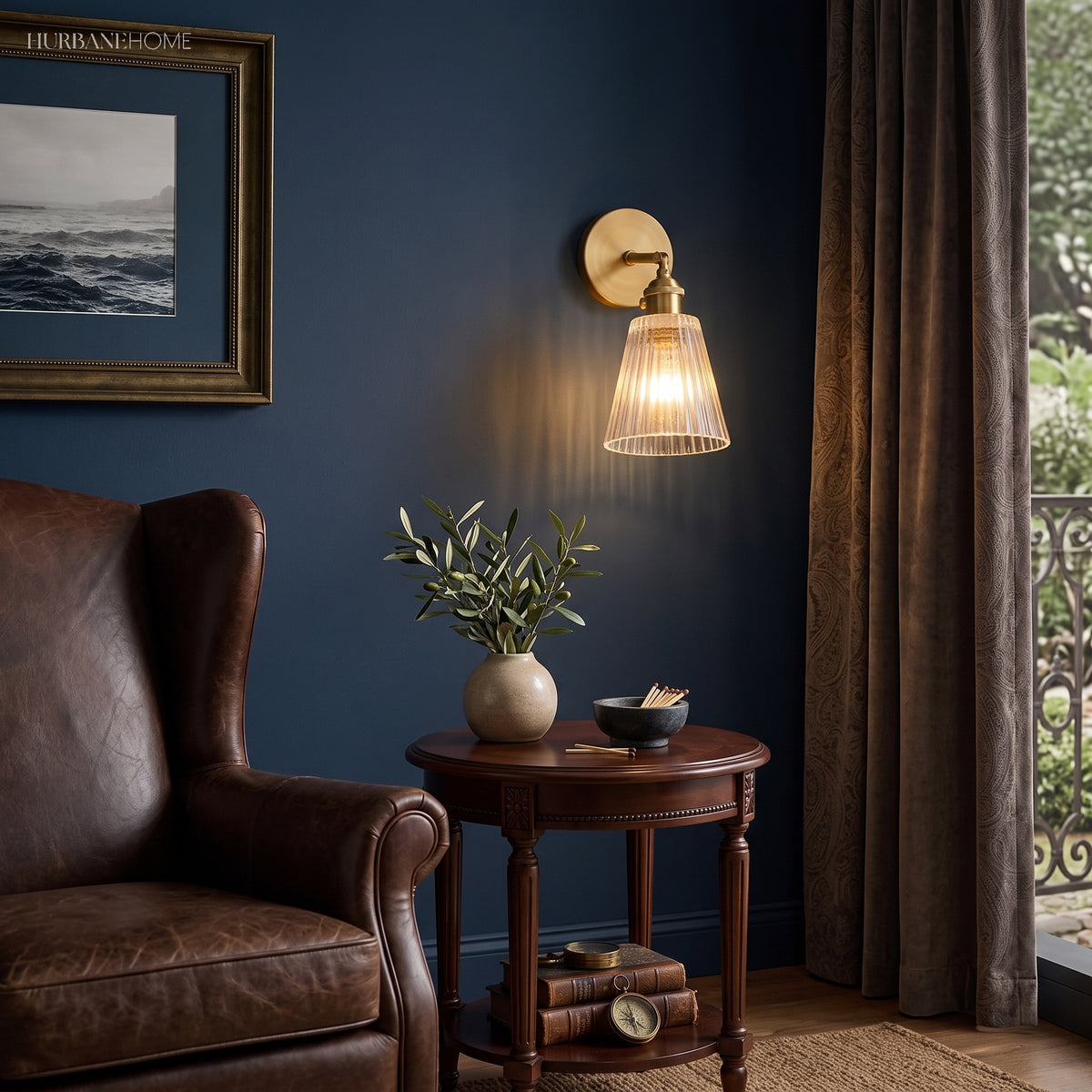 Brass sconce lit on a navy wall above a leather wing chair