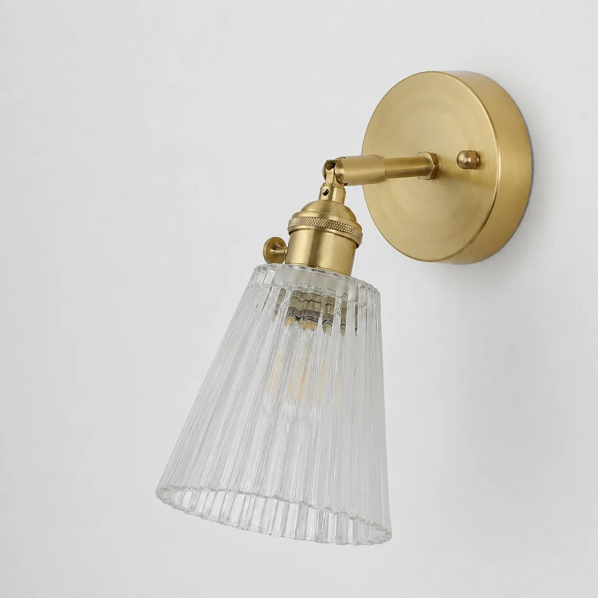 Unlit brass wall sconce seen from the side on a plain background