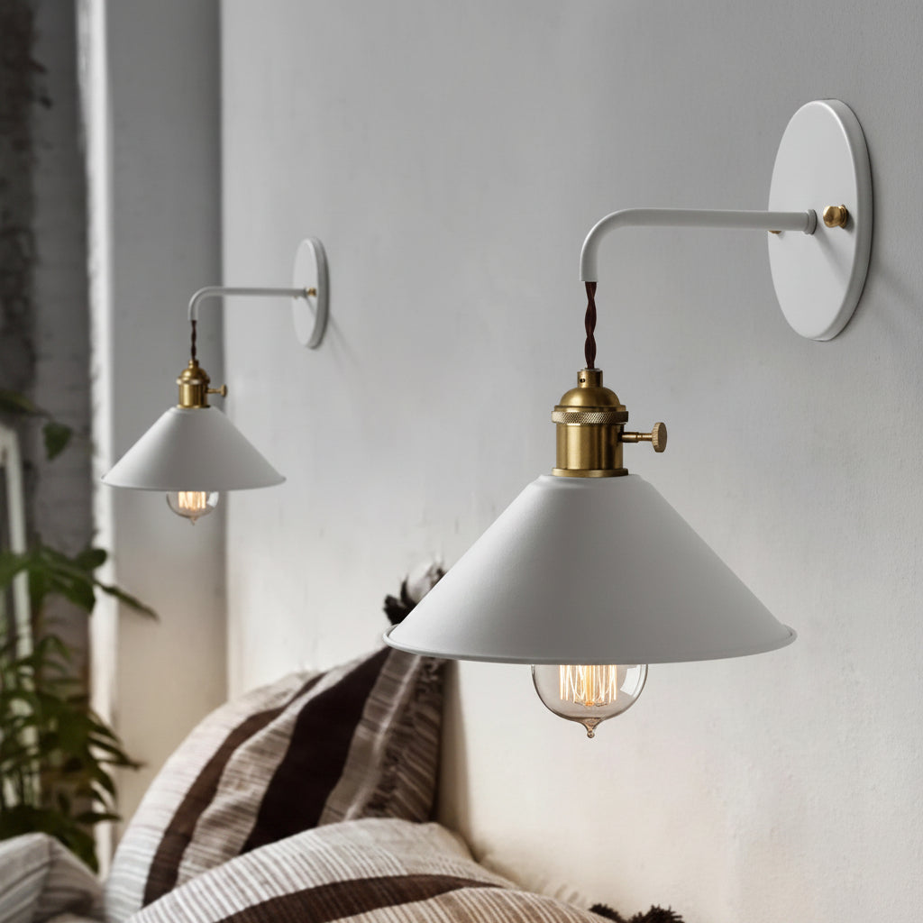 Two white cone shade sconces lit against a plaster wall