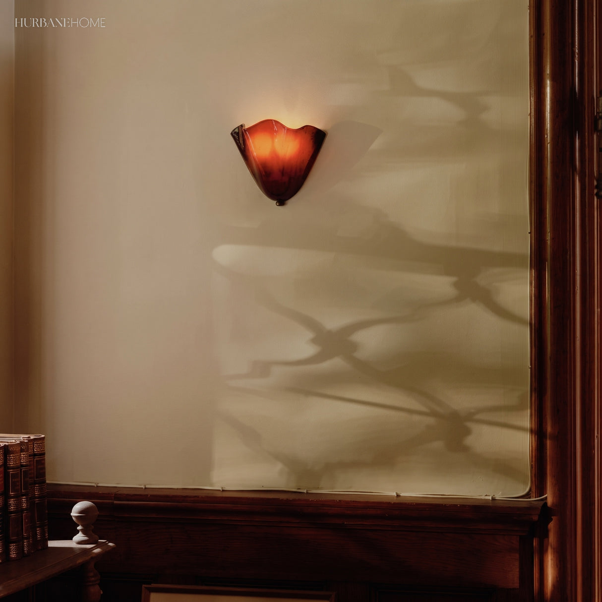Amber frosted glass wall sconce on a panelled interior wall with timber trim